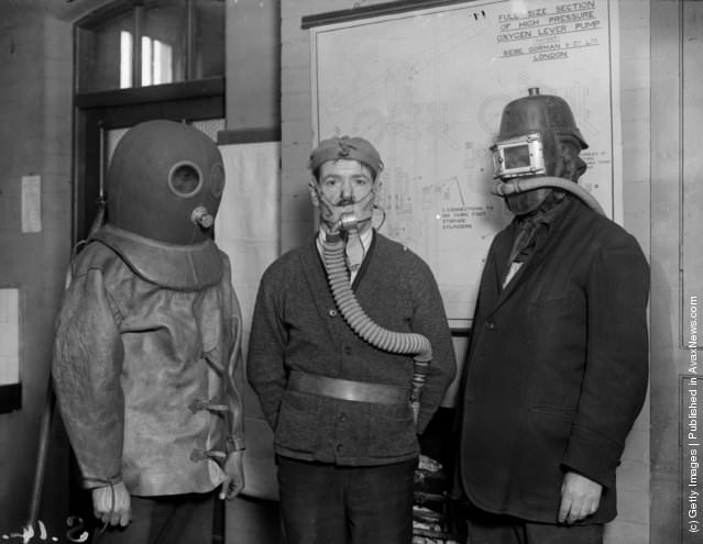 Workers demonstrating different types of mine rescue gas masks, 1925.