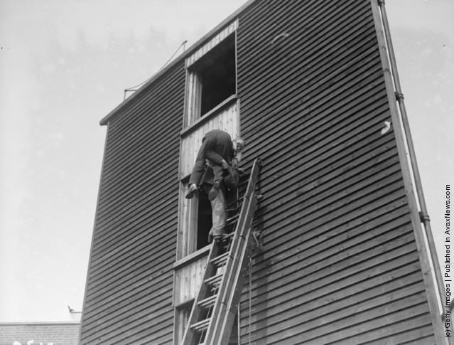 A fireman rescuing someone during a gas mask class for London firemen, 1928.