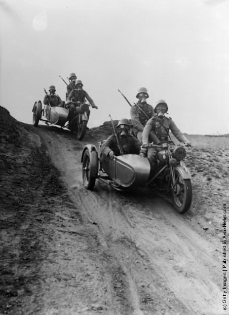 German soldiers in gas masks riding motorcycles during maneuvers, 1936.