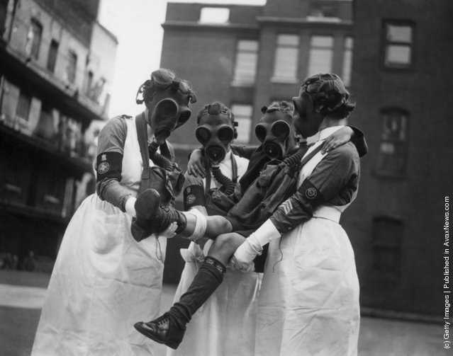 Nurses in gas masks attending a patient during a gas attack demonstration in London, 1935.