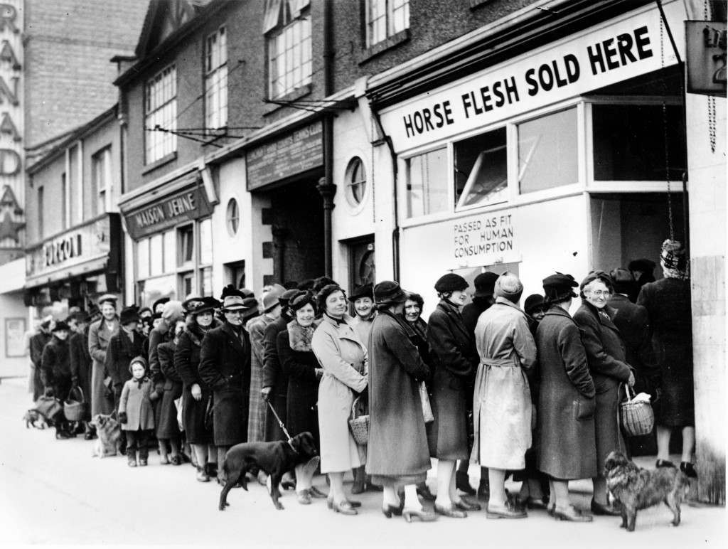 Women line up outside a butcher shop to buy meat in North Cheam, Surrey, 1942.