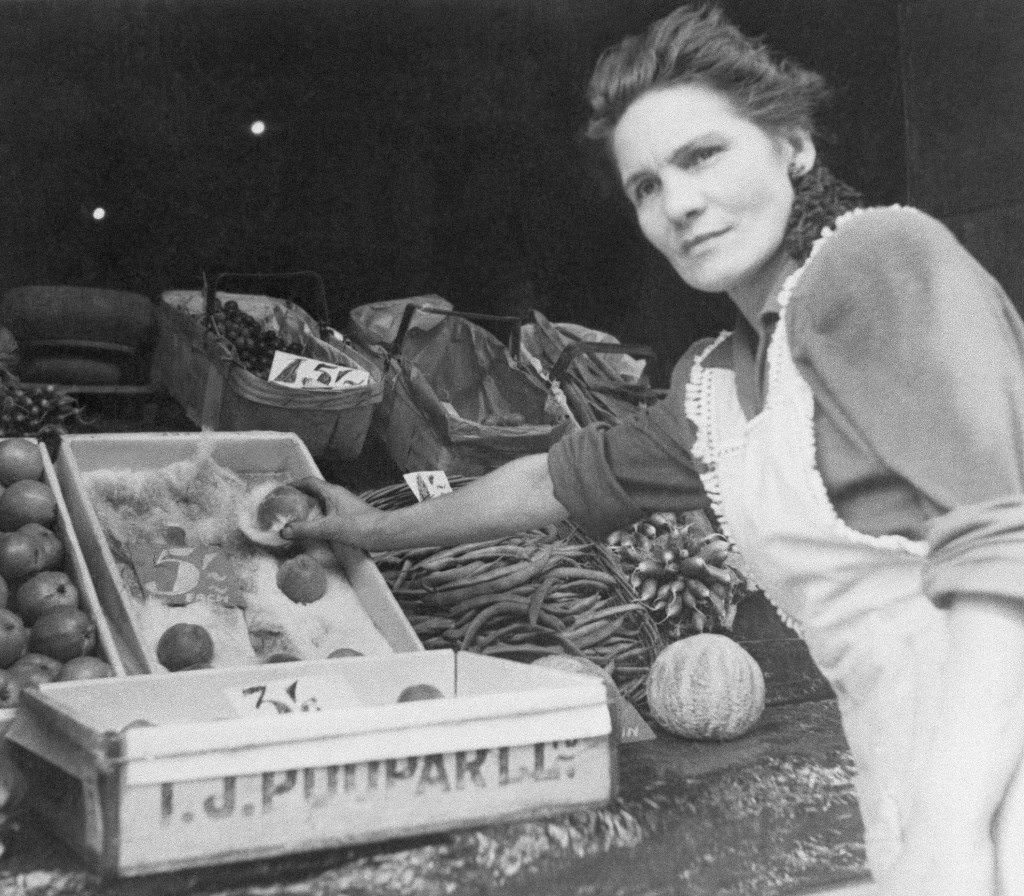 A fruit vendor demonstrates that small peaches cost a dollar each in London, 1944.