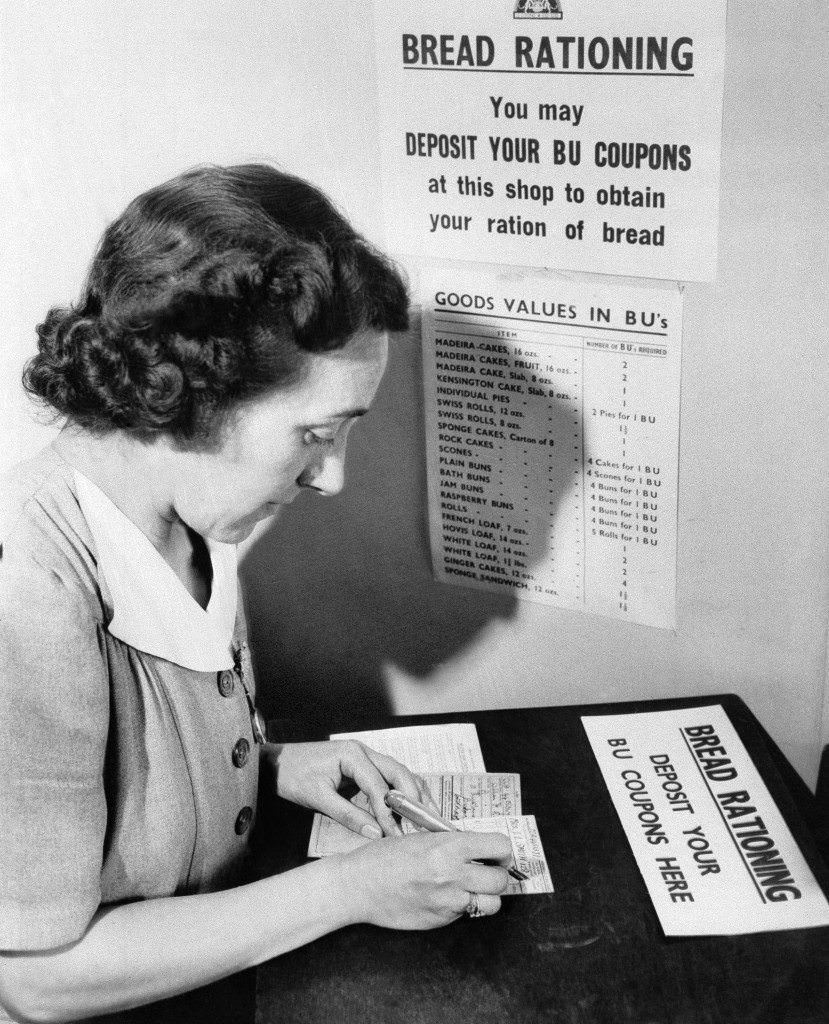 A London housewife fills out her bread unit card in a London shop, 1946.