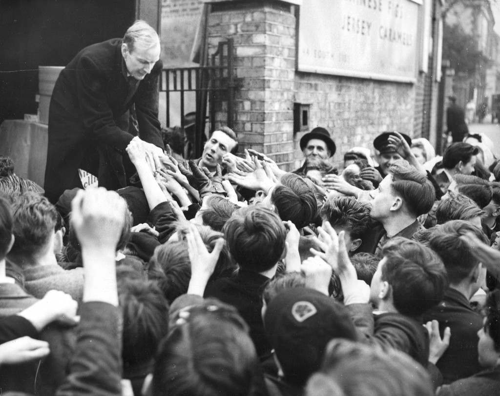 Eager hands of London children stretch out for sweets being distributed for free, 1954.