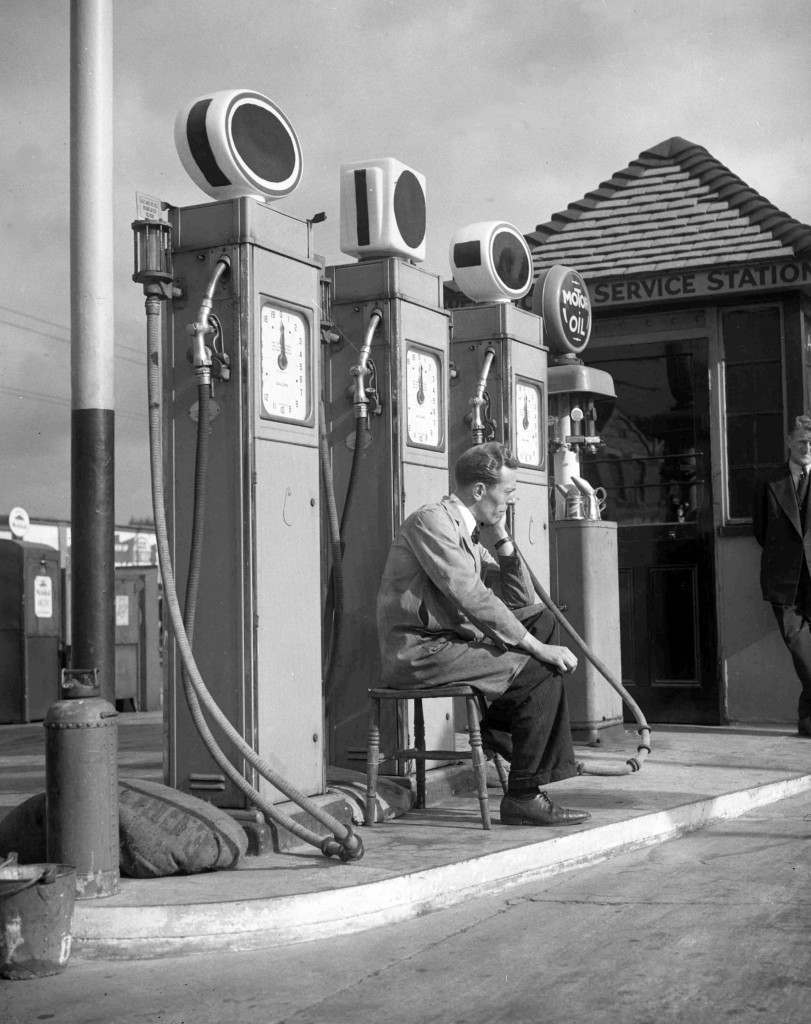 A garage attendant waits for customers at a garage somewhere in London, 1939.
