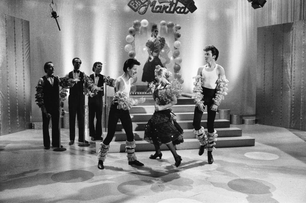 She also did a Latin style cover of A-ha’s “Take On Me,” with background vocals provided by Jon Lovitz, Damon Wayans, and Robert Smigel.