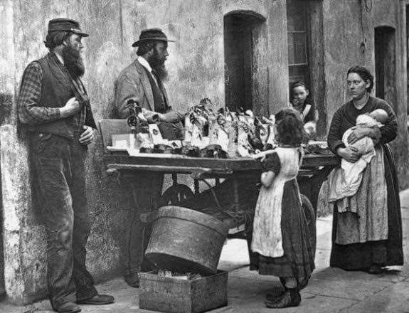 A Victorian fancy wear dealer selling ornaments from his barrow, 1877.