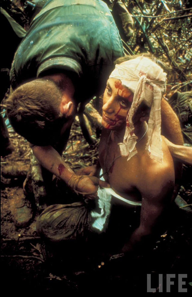Shell shocked wounded Marine being bandaged in muddy jungle during OP Prairie US mil. sweep just s. of DMZ, S. Vietnam.