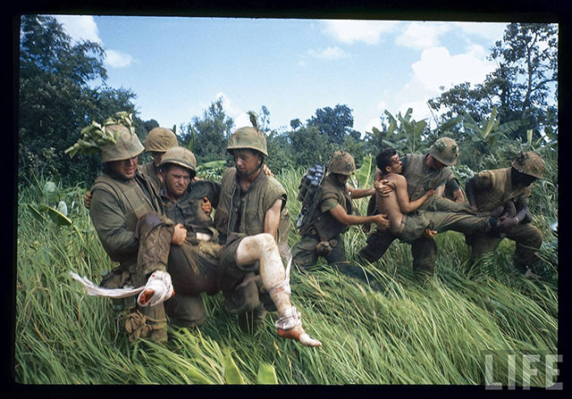 Members of 1st Marine Division carrying their wounded during firefight nr. southern edge of DMZ during Vietnam War. South Vietnam.
