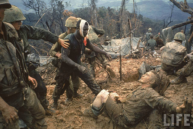Wounded Marine Gunnery Sgt. Jeremiah Purdie (C) being led past stricken comrade after fierce firefight for control of Hill 484 during the Vietnam war.