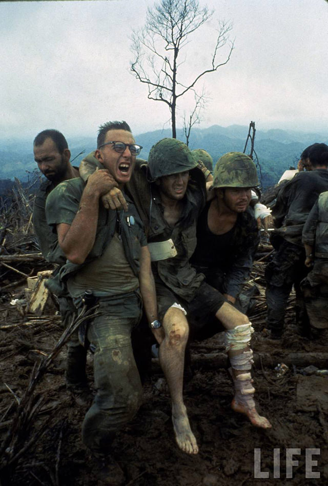 American Marines aid a wounded comrade during intense battle for Hill 484 as part of Operation Prairie being conducted near the DMZ during the Vietnam War.