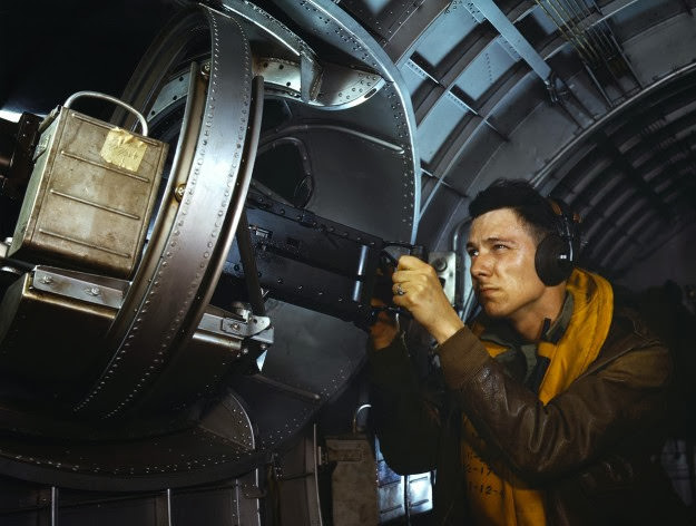 A non-commissioned officer works on a YB-17 bomber machine gun, 1942.