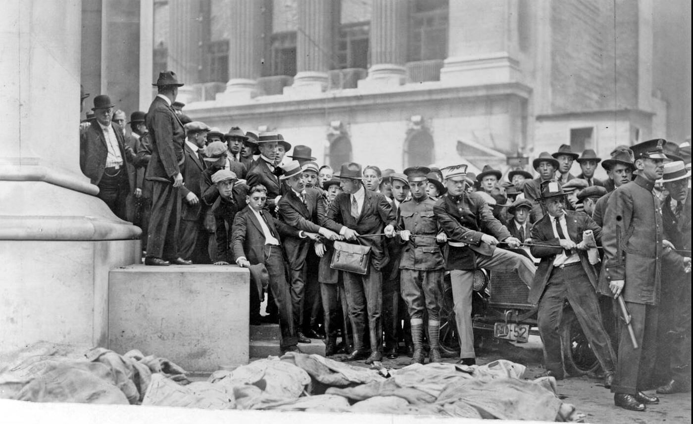 The Wall Street bombing killed 38 and injured hundreds; soldiers and police try to control the crowd viewing the bodies, 1920.
