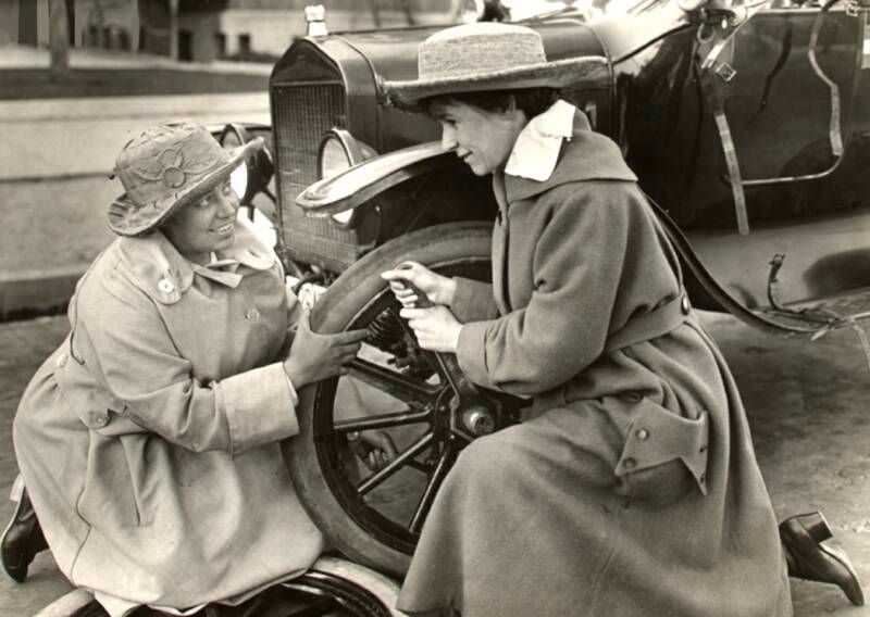 Margaret Whittemore and Margery Rose changing a tire on their car during a suffrage tour, 1916.