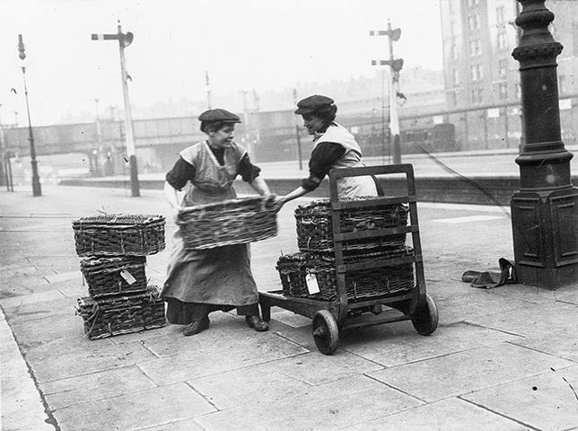 Two women porters at Marylebone station in London loading wicker baskets, 1914.