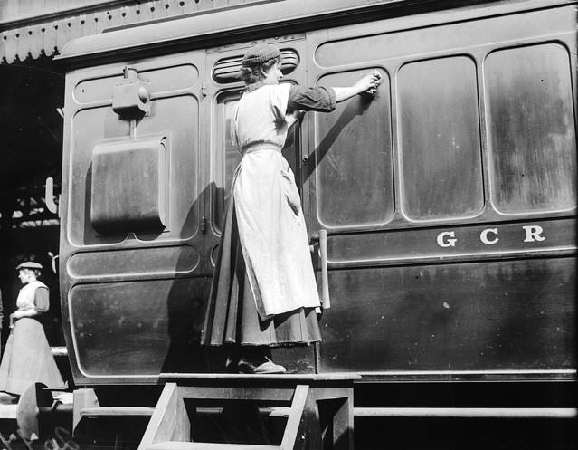 A woman porter at Marylebone Station cleaning a carriage, 1914.
