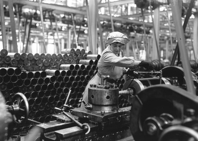 A woman munitions worker operating a machine in an armaments factory during World War I, 1915.