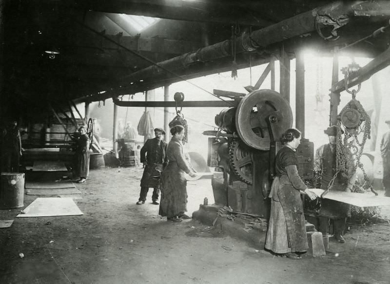 Women assisting at a punching and shearing machine.