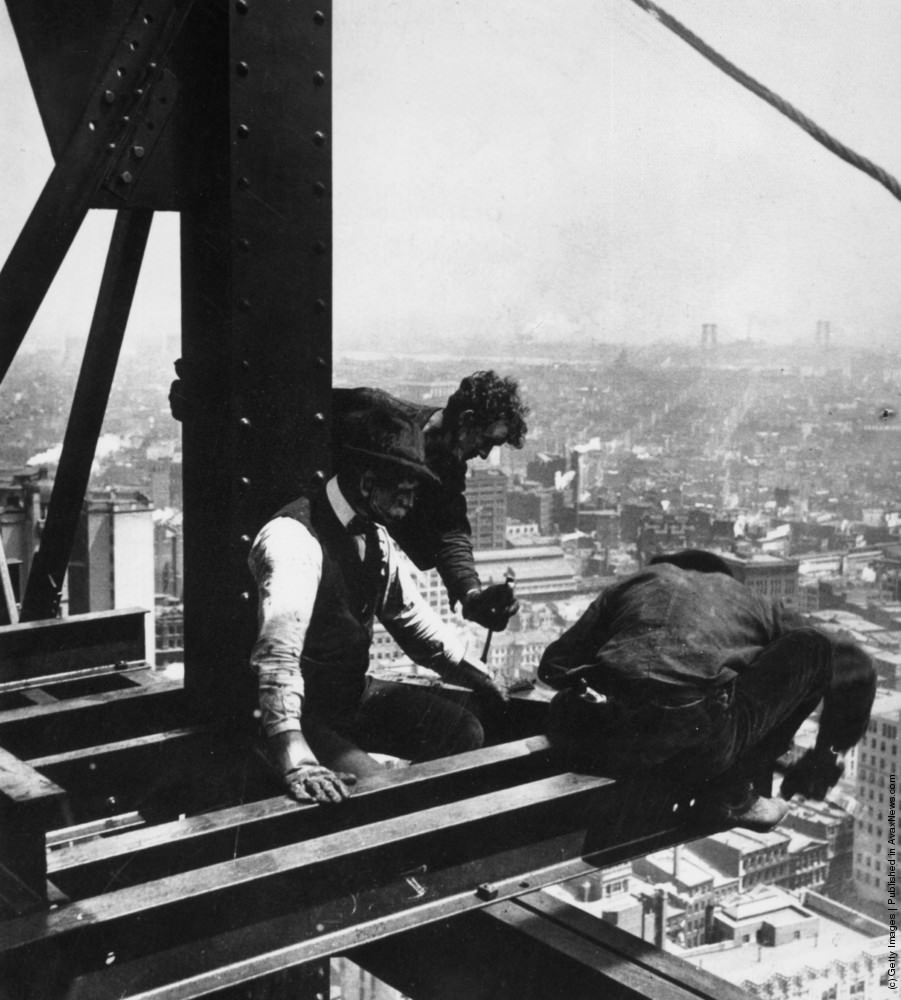 A construction worker crouches over the end of a girder high above the streets of New York, 1930.