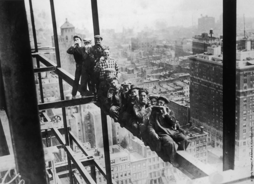 Harmonica playing steel workers perched on a girder on the 22nd storey of the Murray Hill building, New York, 1930.