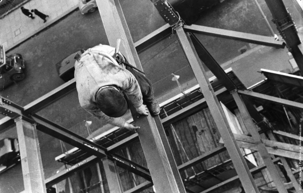 A scaffolder making his way across a steel girder 70 feet above the ground, 1955.