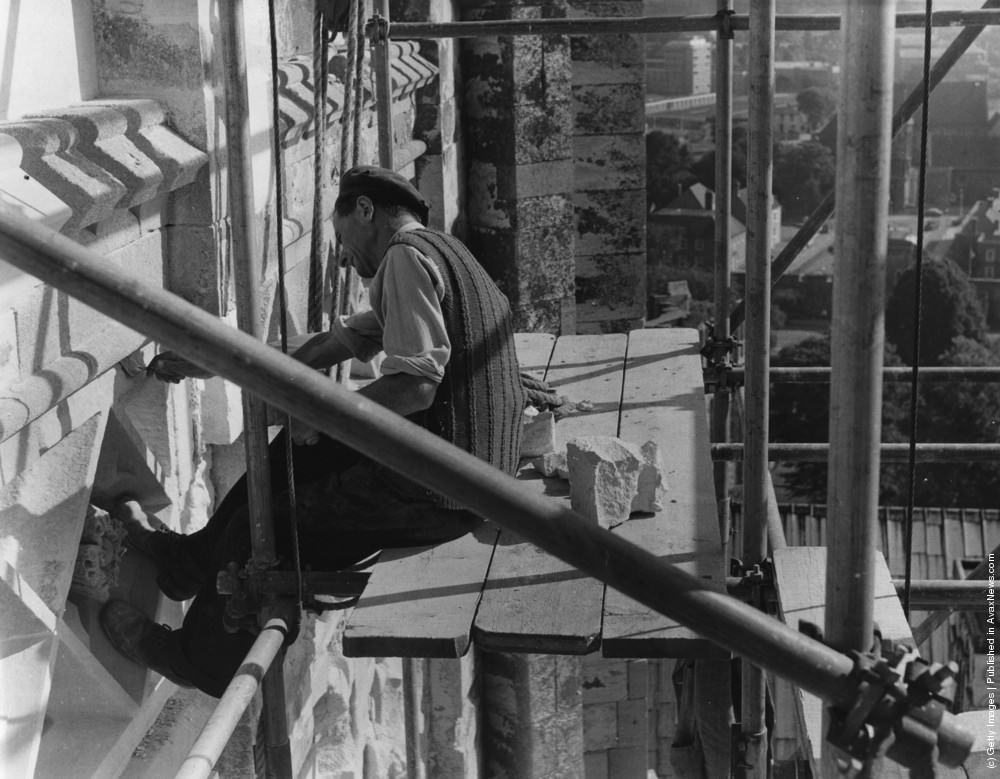 A stonemason at work on the south face of Canterbury Cathedral's Bell Harry Tower, 1964.