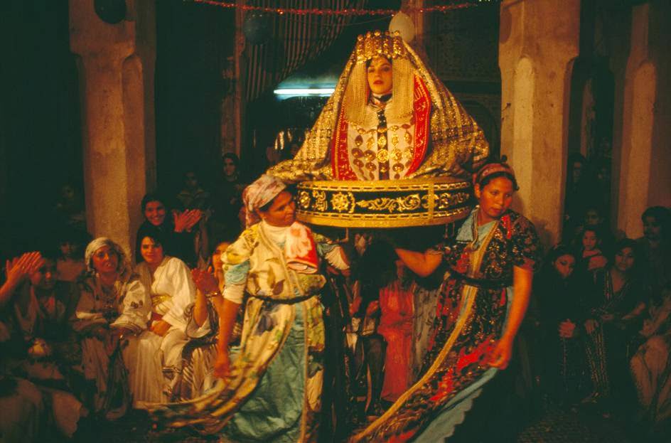 Traditional wedding where arrangers carry the bride wearing a gold dress, 1984.