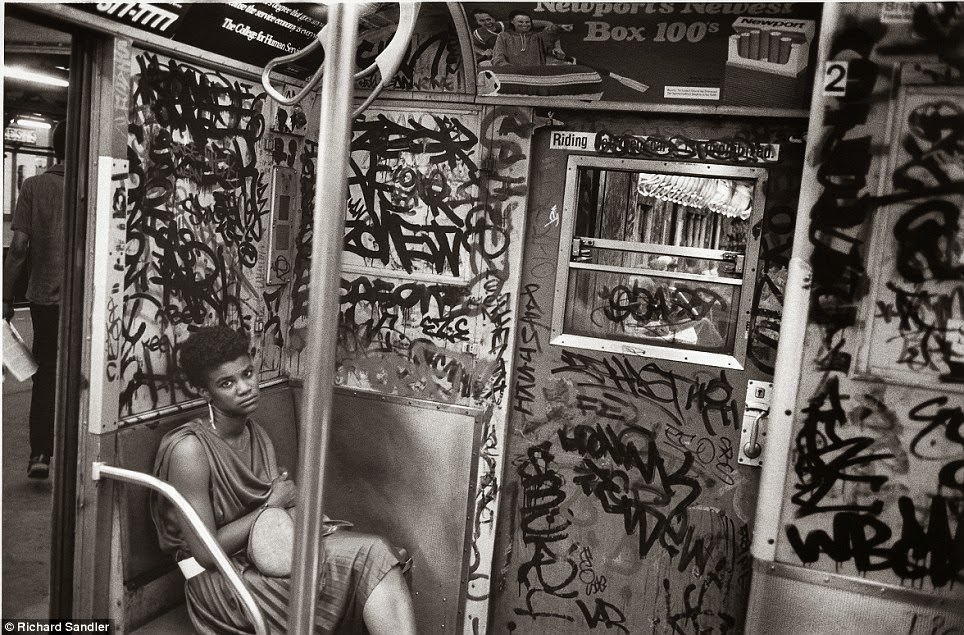 A woman looks up from a subway car covered in graffiti, 1984.