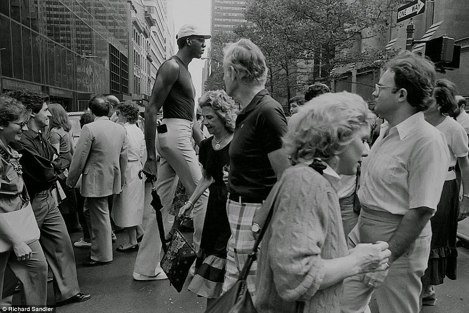 A very tall man towers over other New Yorkers who stare in awe on Fifth Avenue, 1987.