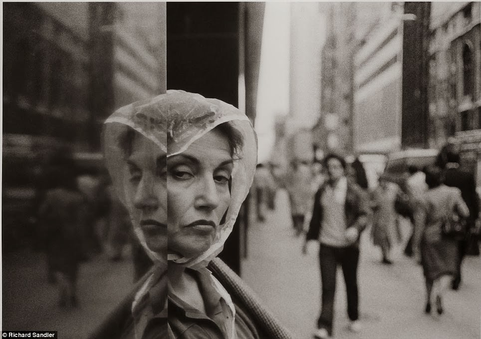 A woman wearing a rain hat peers distrustfully at the camera lens as she stands in a doorway on Fifth Avenue, 1984.