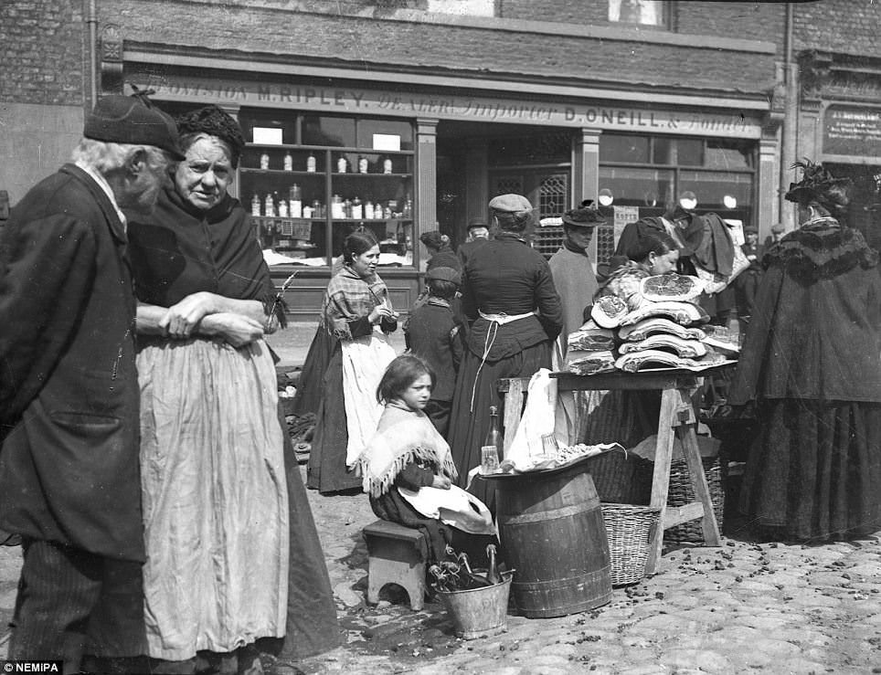 A little girl selling cordial with meat sellers at either Paddy's Market or Bigg Market, Newcastle.