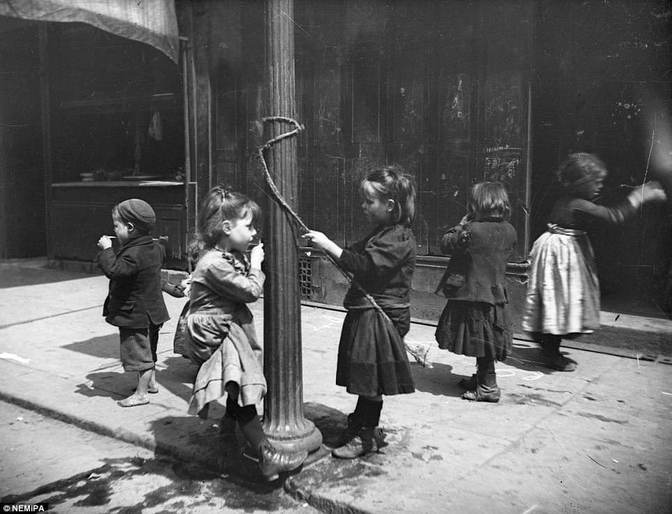 Children skip and play around a lamp post.