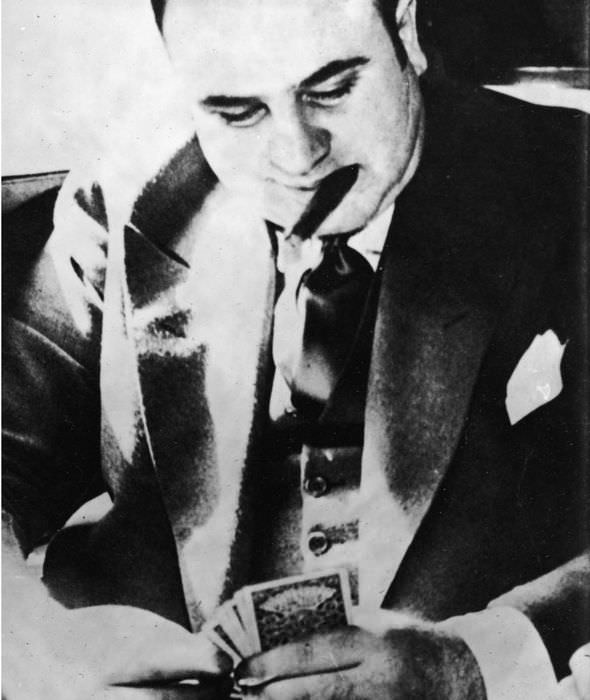 Capone plays cards during his transport to prison for tax evasion.