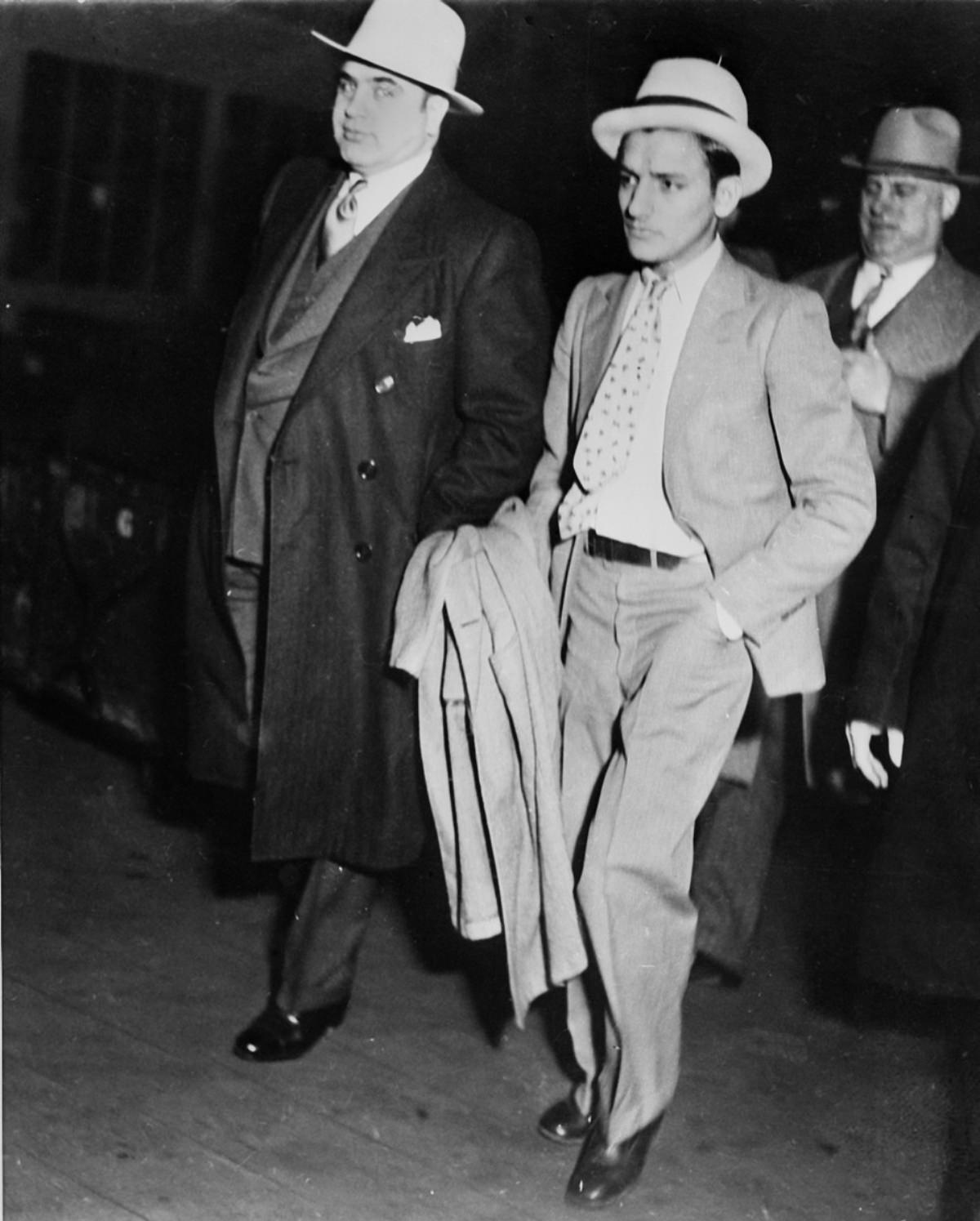 Capone handcuffed to a convicted automobile thief being marched through a train station in Chicago to board a special car to Atlanta Penitentiary, May 3, 1932.