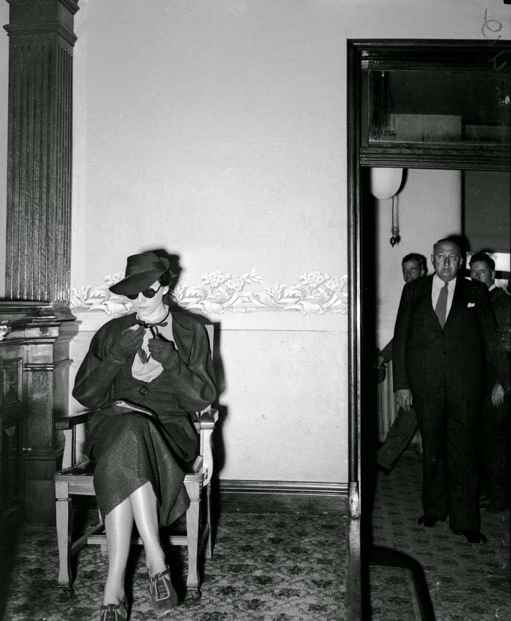 Mrs. Frances Birch, 32-year-old widow of Rock Island, as she appeared on the witness stand in Oregon, Ill. on Oct. 19, 1936, at the murder trial for Guy M. Tallmadge. Tallmadge, who was described by the newspaper as "bald-headed and paunchy" was an assistant undertaker in Rockford who shot and killed his wife Bessie, 51, along a gravel road six miles east of Oregon, Ill. on May 19, 1936. It was Bessie's birthday. Tallmadge, who had been dating Birch on the side, had given the young widow an engagement ring and said he had asked his wife for a divorce. "I don't know why he would do anything like that," Birch said in reference to the murder according to newspaper reports. Later she was ordered to remove her dark sunglasses, which she had worn since the beginning of the trial.