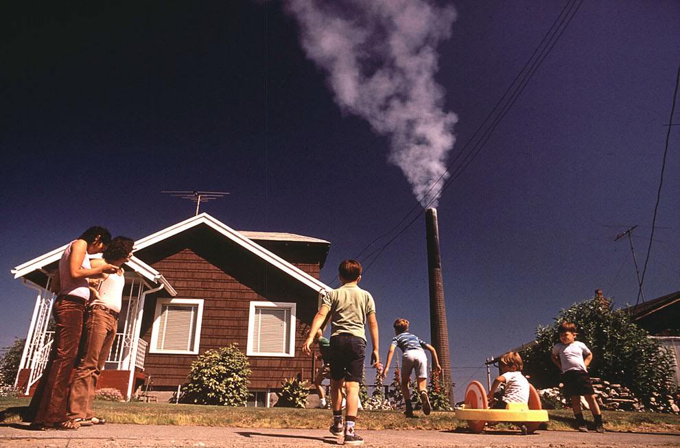 Children play in the yard of a Ruston, Washington home, while a Tacoma Smelter stack showers the area with arsenic and lead residue, 1972.