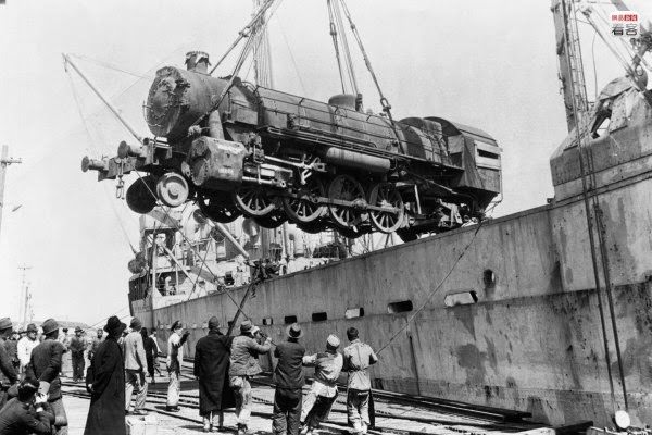 On Shanghai’s booming docks, cargo both large and small transferred. Photo is of dockers unloading a train locomotive engine; this engine car was provided by the United Nations Relief and Rehabilitation Administration. In addition to this, the UNRRA also provided many train cars, railroad ties, and steel rails.