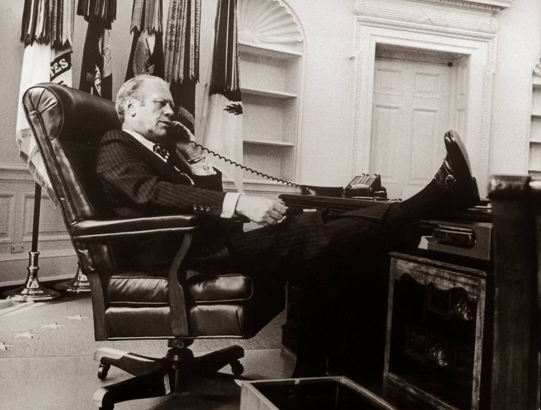 President Gerald Ford, seated in an armchair with his foot on the desk, talking on the telephone in the oval office, Washington, D.C. circa 1974.