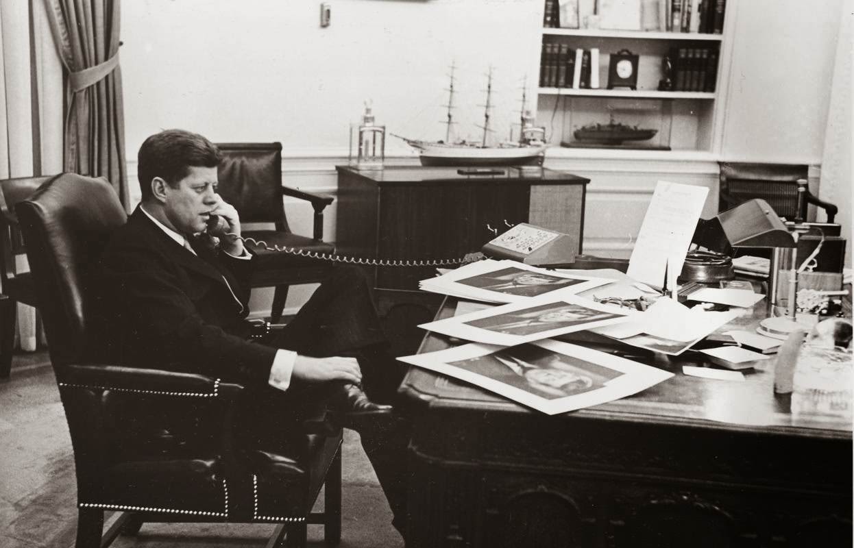 President John F. Kennedy ends his official day with a final phone call to his press secretary from his Oval Office desk at the White House in Washington, D.C., 1961.