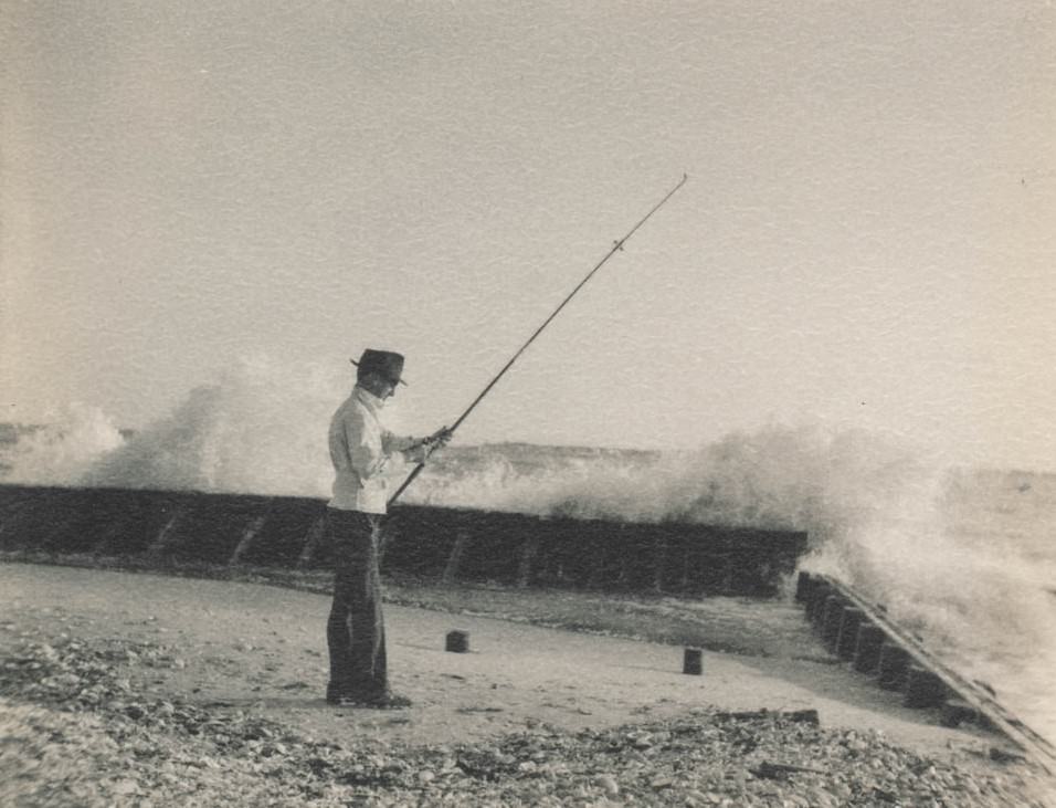 Man fishing while waves breaking.