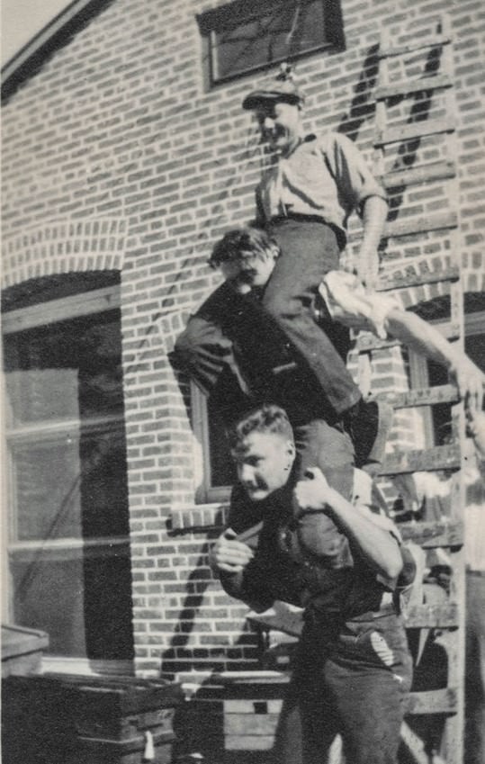 Three young men riding on each others' shoulders.