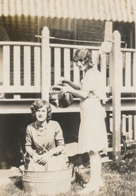 Women bathing in an outdoor barrel.