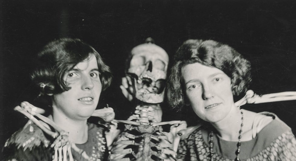 Women pose with their skeleton friend.