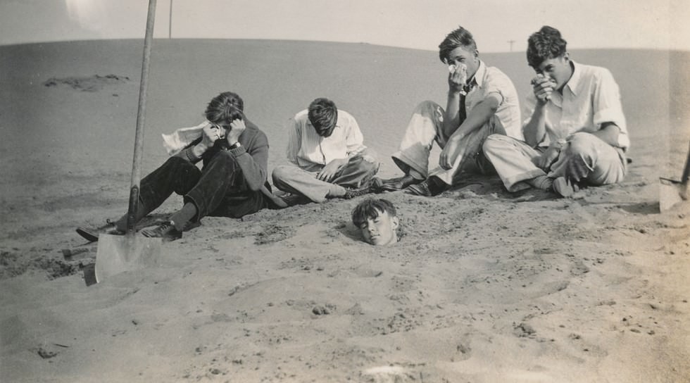 Young men mourning their friend buried in the sand.