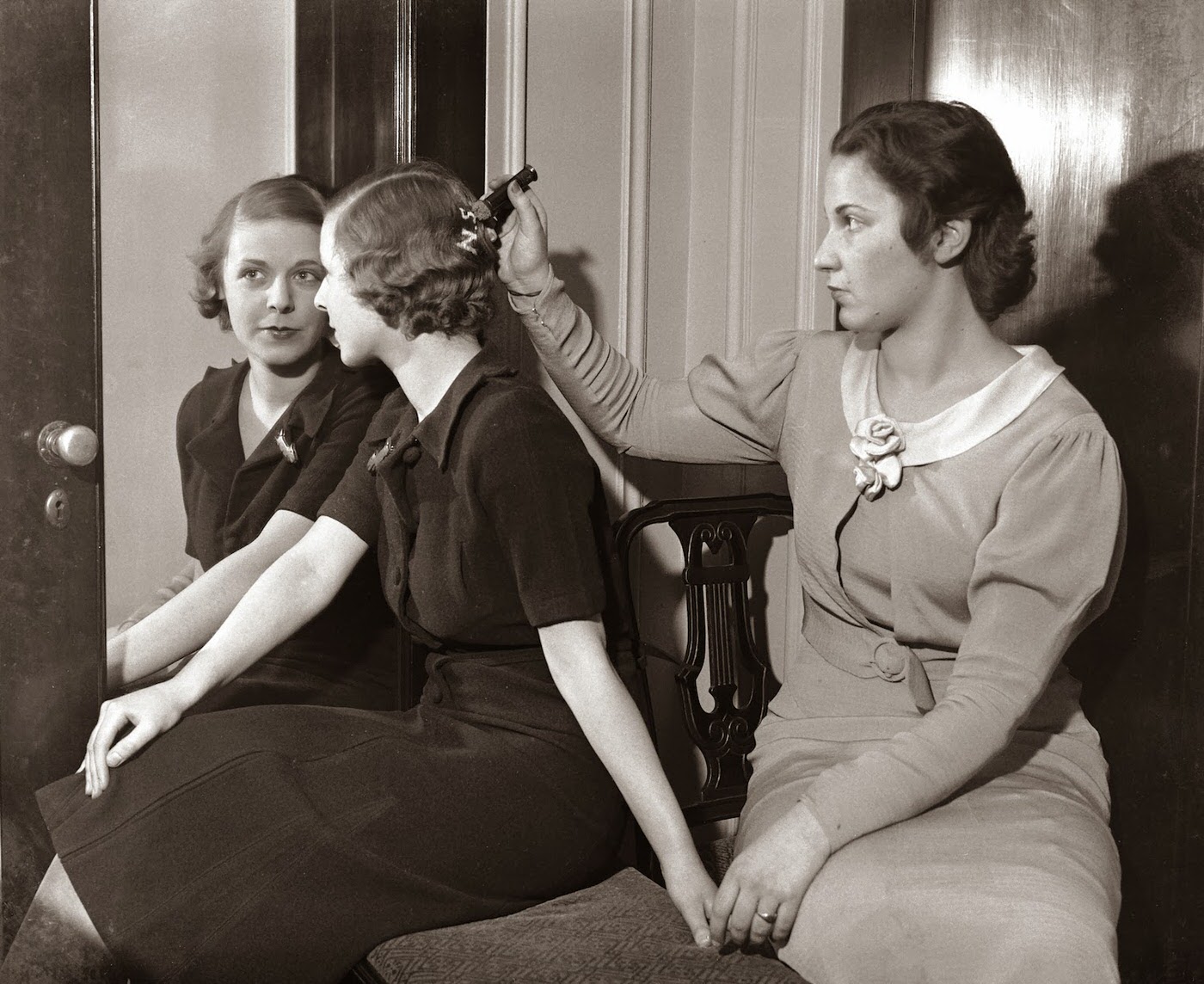 March 21, 1933. Women demonstrate a new gadget that enables young women to wear their “hearts on their hair.” A tricky little fountain gadget outlines the initials of their “best beau” on the hair. It is expected that this vogue will take the place of fraternity pins, diamond rings, etc.