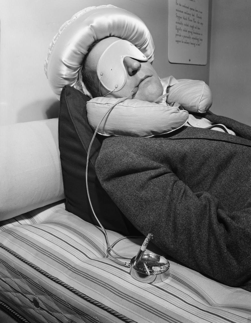 Circa 1950. Garry Moore uses a special device for smoking to prevent the burning of his bedclothes should he fall asleep with a lit cigarette. Photograph by Bettmann/Corbis.