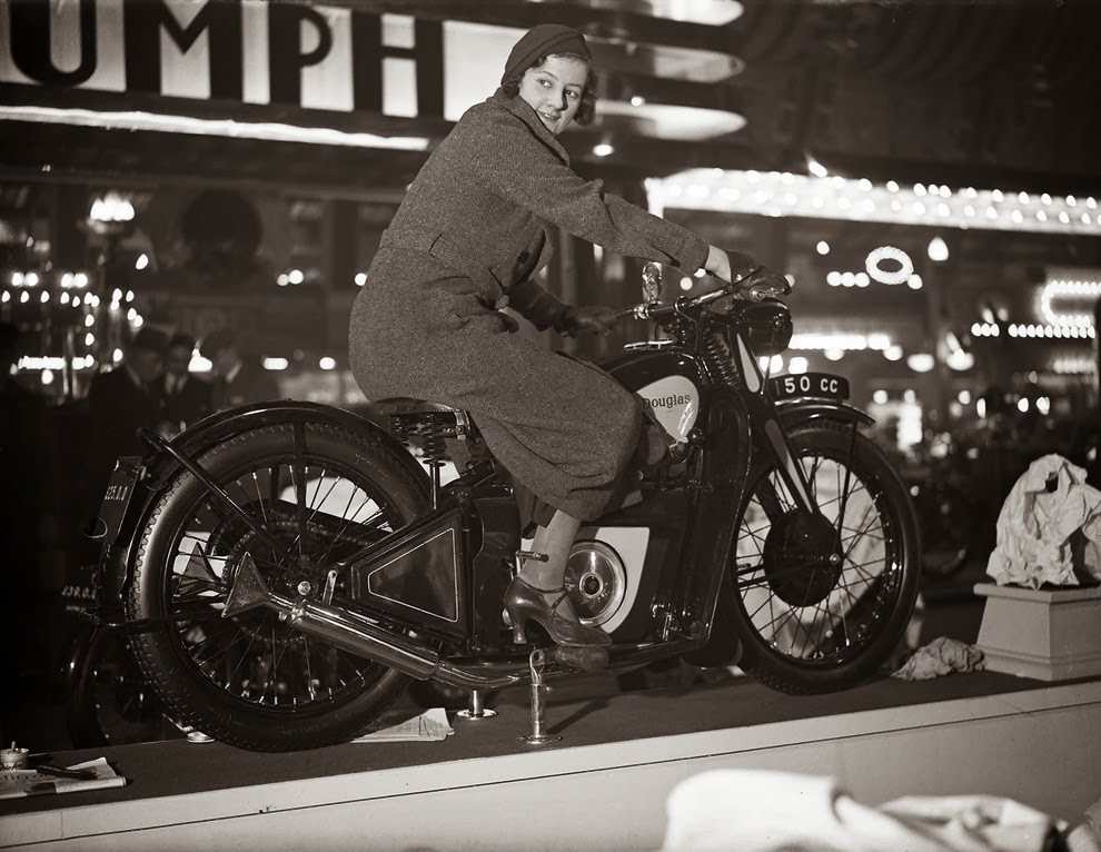 A woman trying out a Douglas motorcycle on display at the 18th Cycle and Motorcycle Show in London, 1933.