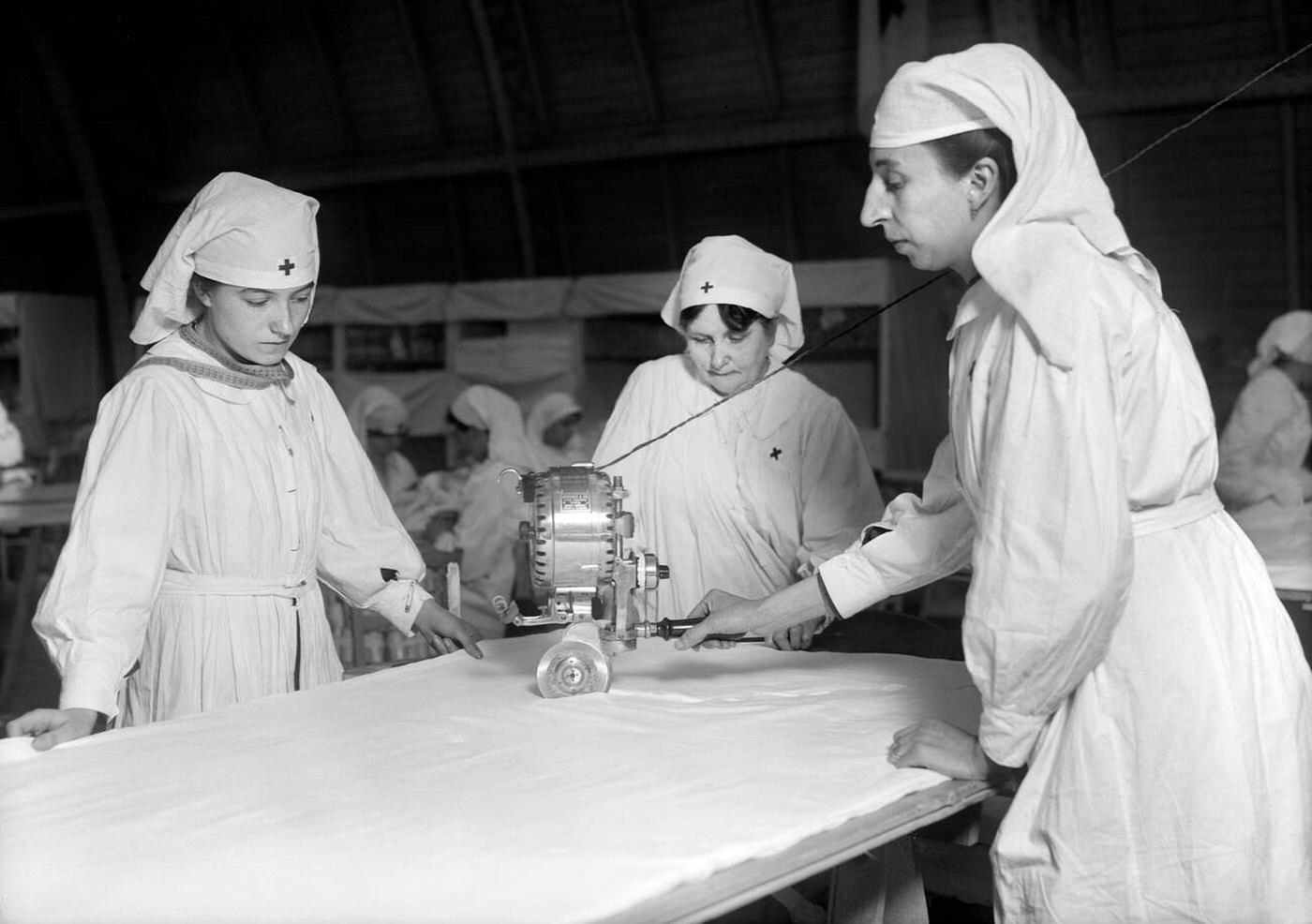 Female American Red Cross Workers cutting Unbleached Muslin for Bias Bandages with Cutting Machine in Paris, France, 1918.