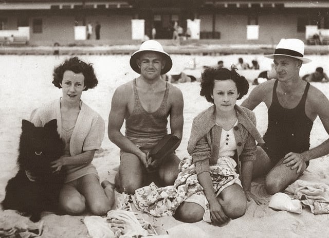 Group of young people enjoying a day at the beach with their dog, ca. 1935