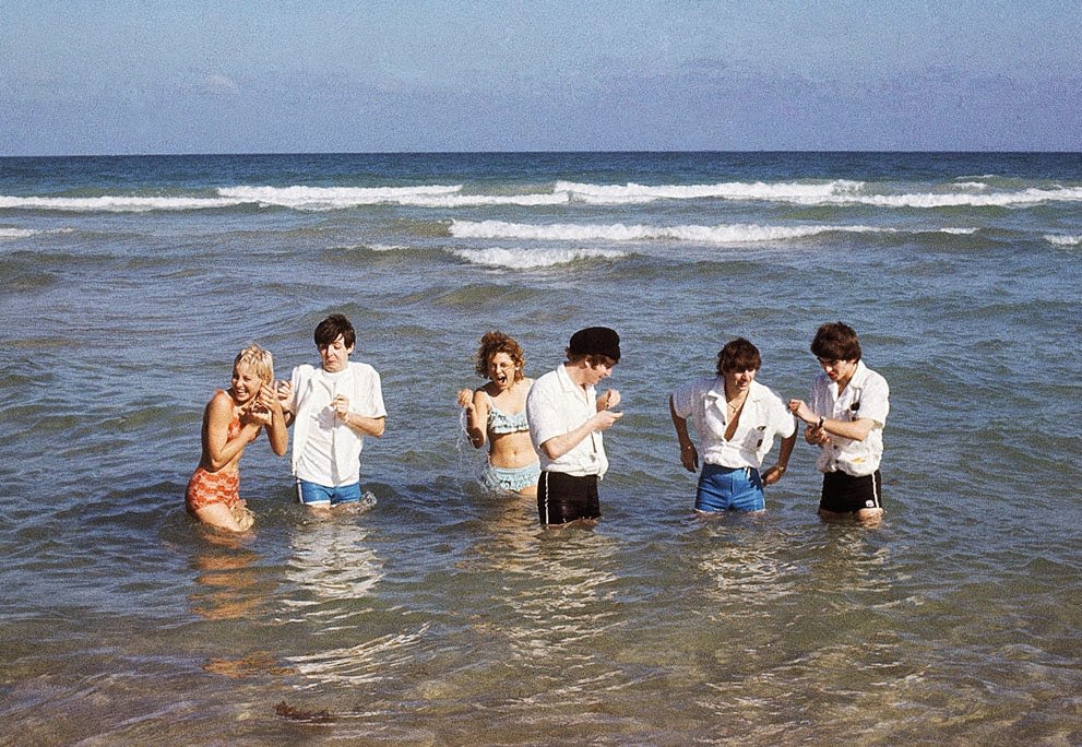 The Beatles wade in the surf in Miami, Florida, with unidentified women, 1964.